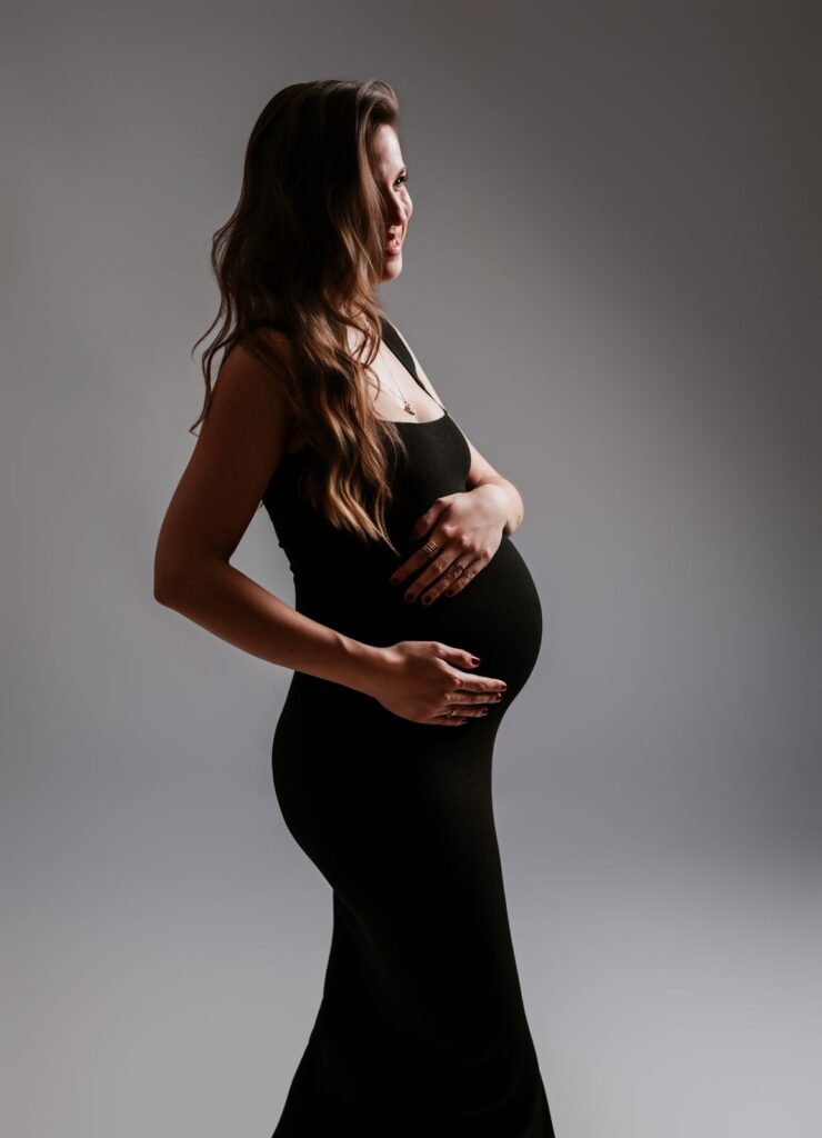 Futura mamá de perfil con vestido negro ajustado