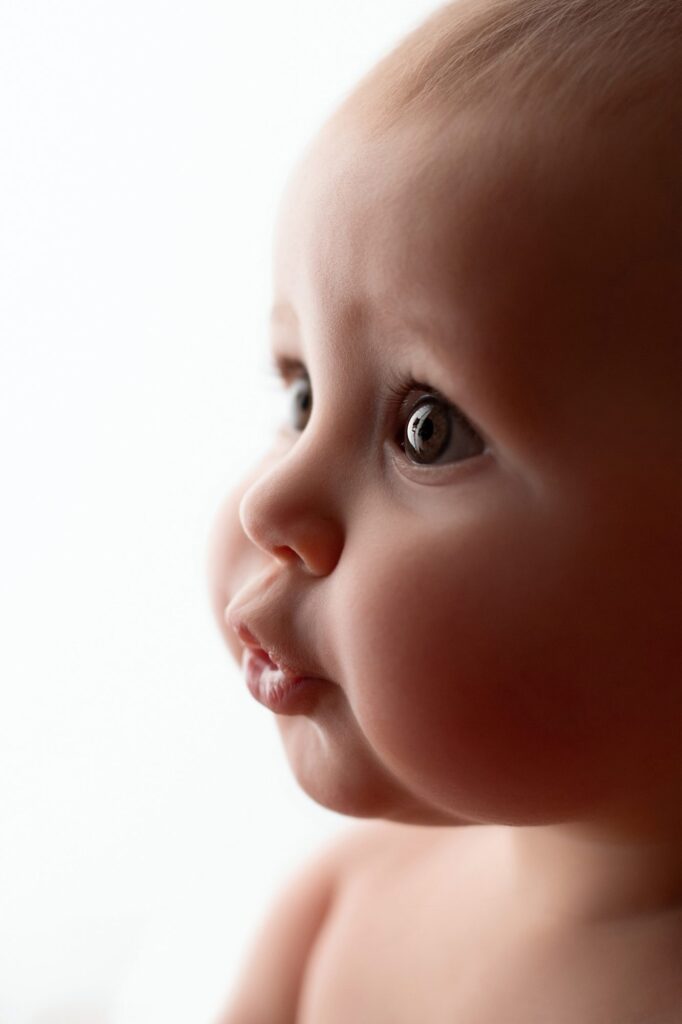 Retrato de perfil de un bebé con mirada curiosa sobre fondo blanco