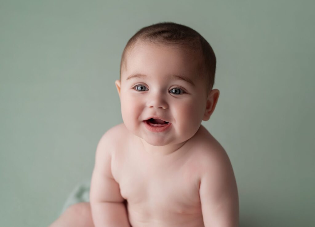 Bebé de seis meses sentado y sonriendo en una sesión sitter en El Escorial